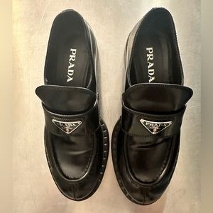 Prada retro-inspired loafers with iconic enameled triangle logo.